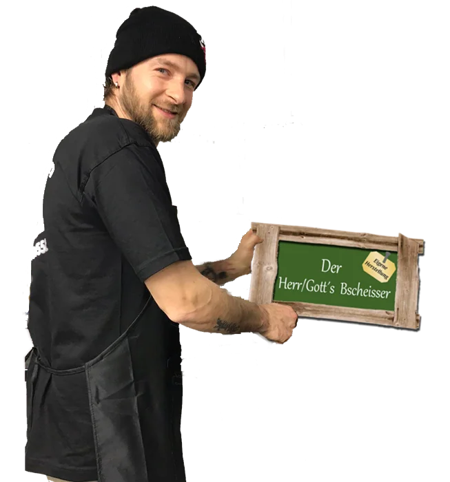 Daniel Böttcher mit dem Holzschild „Der Herr/Gott’s Bscheisser“